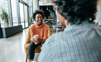 woman sits with business coffee looking at man with smile