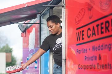 Woman hands food out of her food cart window