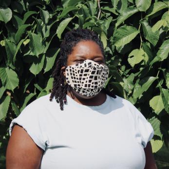 summer brown, a black femme therapist, stands in front of greenery