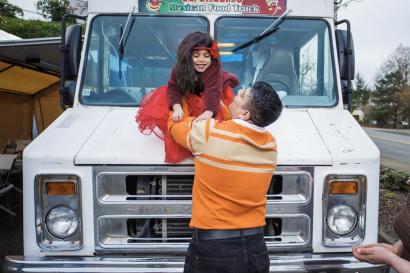 Man holding a child above a food truck