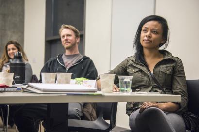 Three people sit at a desk during a business class