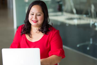 Woman in red shirt types on a laptop