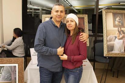 Man and woman embrace in front of artwork