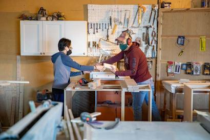 A boy and a man work in a workworking shop