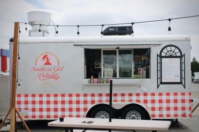 A silver food truck with the words "southern girl delights" sits in a cart pod on an overcast day