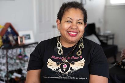 Woman sits in her home wearing the jewelry from her small business