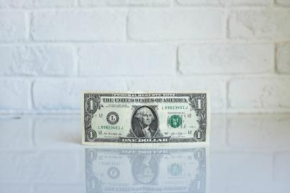U.s. one dollar bill in front of white brick wall
