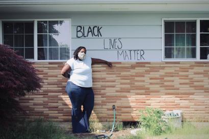 Summer brown, a black femme therapist, stands in front of text reading "black lives matter" at her home
