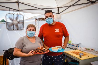 Elvia and raymundo stand in with chicken, rice and beans on a plate ready to serve