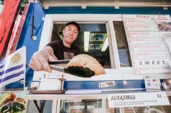 Man handing an empanadas through store window.