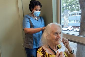 A caregiver works with a female client using safety precautions in-line with covid guidelines and standards