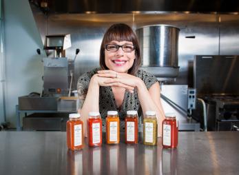 Woman leans above a selection of her hand-crafted hot sauces