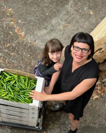 Woman and daughter stand next to fresh produce