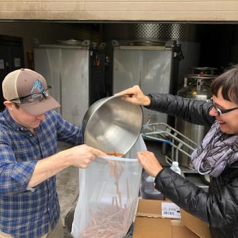 Man and woman pour veggies into bag for making hot sauce