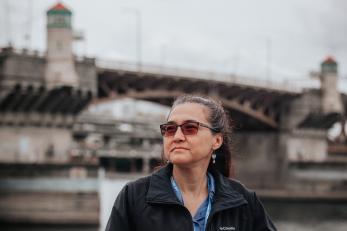 Woman in front of urban bridge.