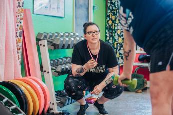 Woman crouching in an exercise facility.