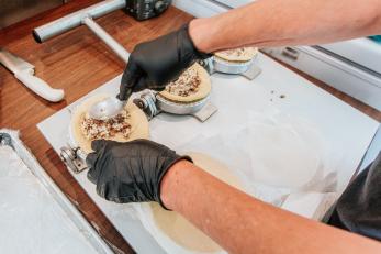 Hands filling empanadas.