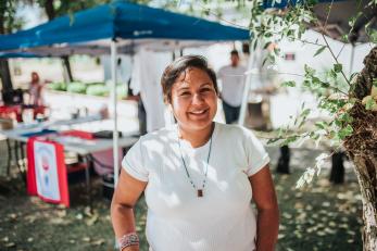 Woman standing in "farmer's market" venue in front of tent.