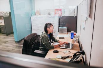 Woman in office typing on a computer.