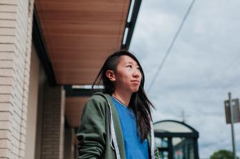 Woman standing in front of office looking up.