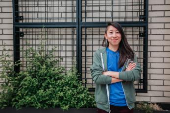 Woman standing in front of wall with arms crossed and smiling.