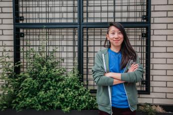 Woman standing in front of wall with arms crossed and smiling.