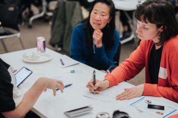 two women filling out forms at a table