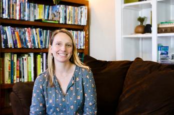 woman with blonde hair and blue shirt sits on her couch