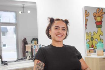 latina woman with a bright smile sits in hair salon chair of business she owns