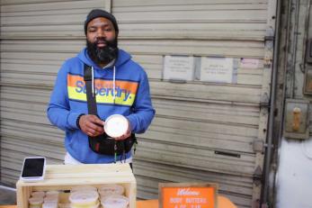 man holds product from his skincare line for camera