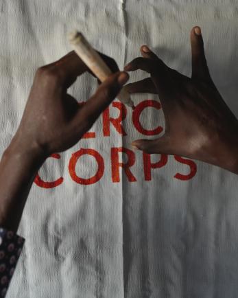hands writing over Mercy Corps logo