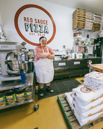 female cook standing in pizza kitchen