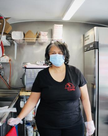 The owner of Southern Girl Delights stands in her food truck kitchen in a black shirt