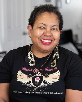 woman sits in her home wearing the jewelry from her small business