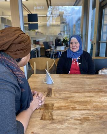 two women in hijabs sit at a table 
