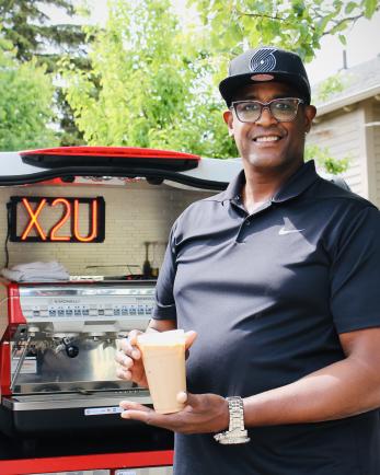 Eddy Holford holding beverages he made with his mobile café business vehicle.