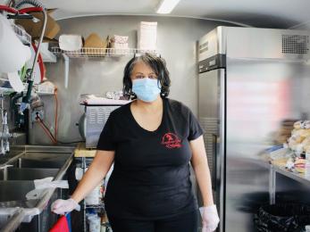 Dorothy golson stands in her food truck kitchen wearing a face mask and gloves as personal protective equipment